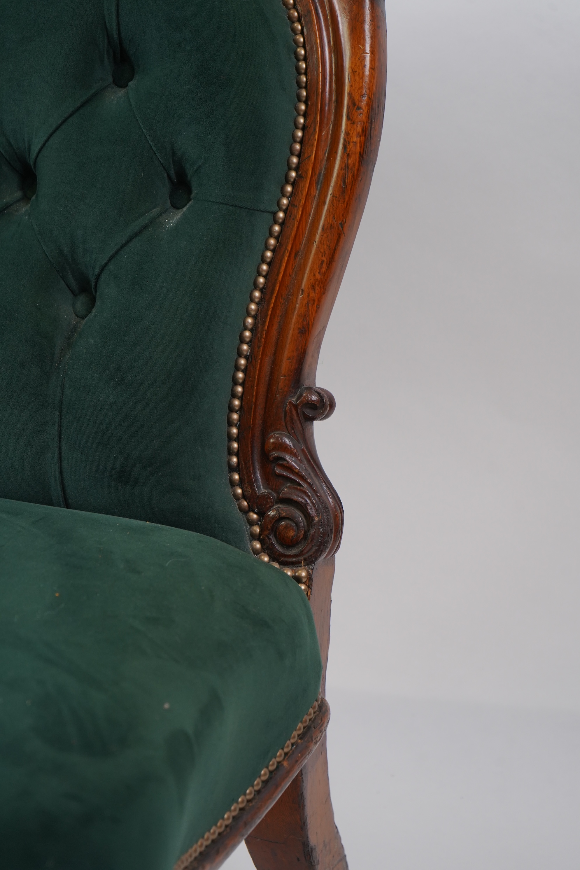 A pair of Victorian carved oak settees, recently re-upholstered in deep buttoned green velvet, the scroll carved crest rails over serpentine seats on cabriole front legs, 160cm wide, 96cm high, Provenance - previously gi